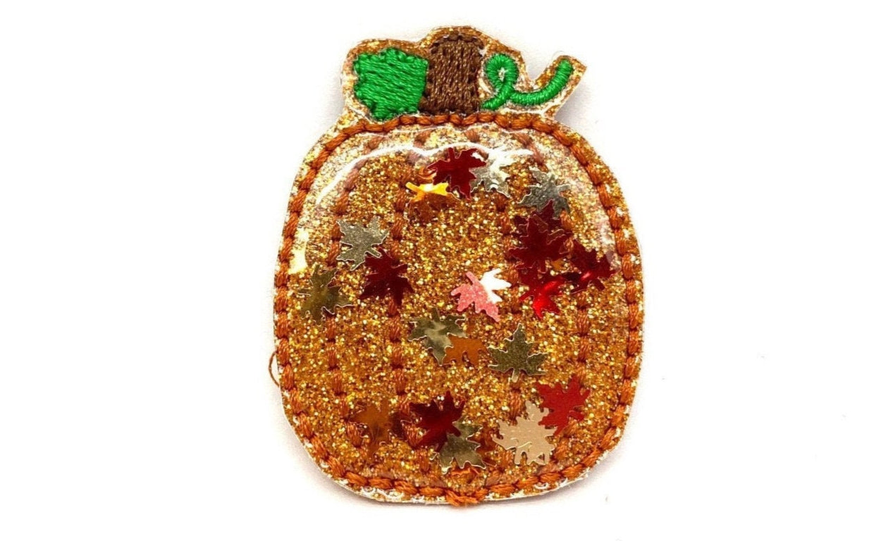 Orange and clear pumpkin dog collar charm filled with fall leaf confetti, attached to collar with an elastic loop.