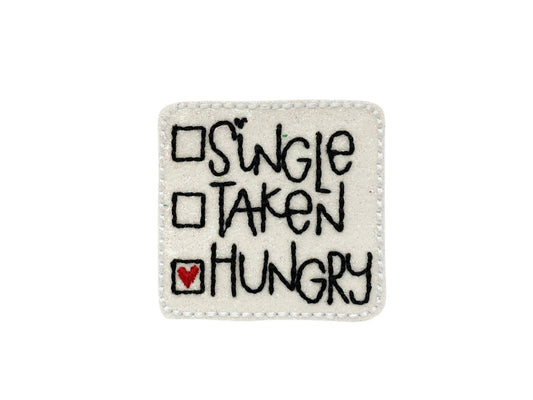 Sparkly square Valentine’s Day dog collar embellishment with the phrase "Single, Taken, Hungry", attached by an elastic loop.