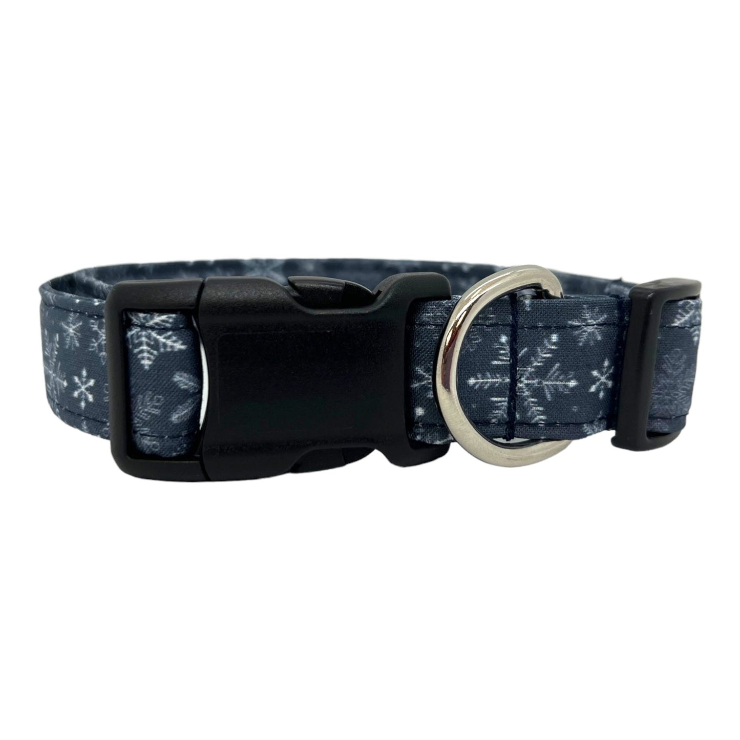 Navy blue dog collar decorated with white snowflakes scattered across the fabric, shown flat to highlight the crisp winter pattern.