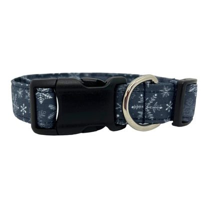 Navy blue dog collar decorated with white snowflakes scattered across the fabric, shown flat to highlight the crisp winter pattern.