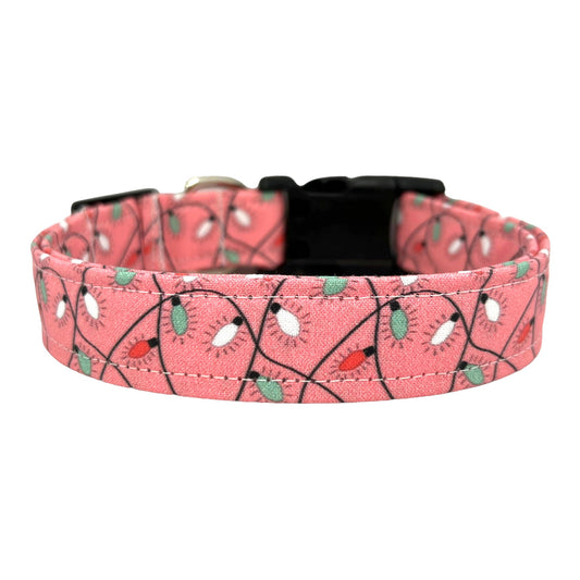 Pink dog collar decorated with a colorful string of Christmas lights, shown flat to highlight the festive holiday design.