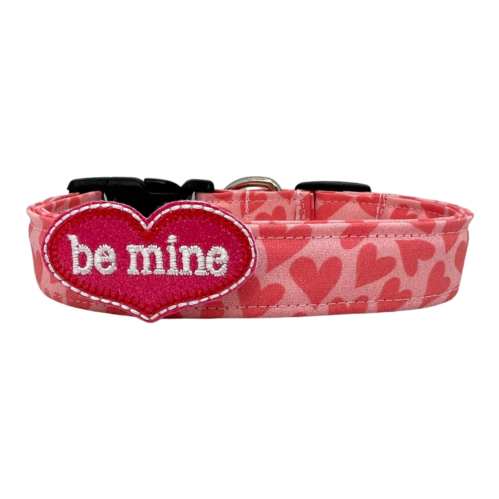 Pink Valentine’s Day dog collar with heart pattern and removable red “Be Mine” heart embellishment attached to a sturdy pet collar