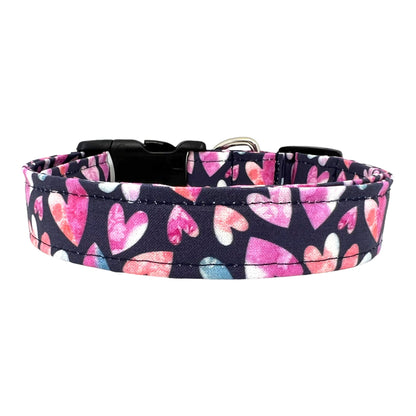 Valentine’s Day dog collar with pink and blush watercolor heart pattern on a navy background, shown flat with buckle and hardware visible.