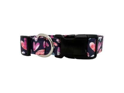 Valentine’s Day dog collar with pink and blush watercolor heart pattern on a dark background, shown flat with buckle and hardware visible.