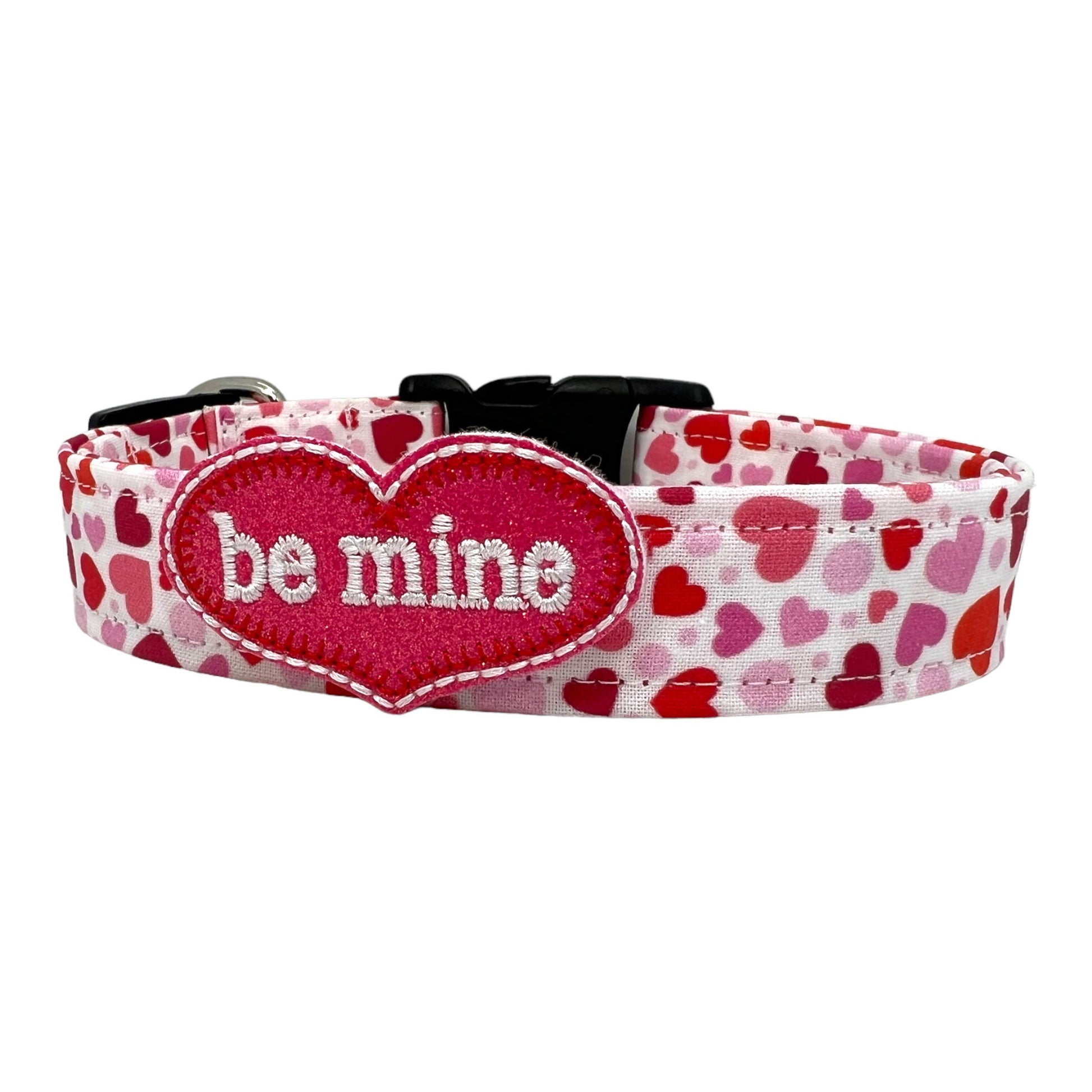 Valentine’s Day dog collar featuring red and pink hearts in various sizes, with be mine heart shaped dog collar embellishment. Heart-themed dog collar shown flat.