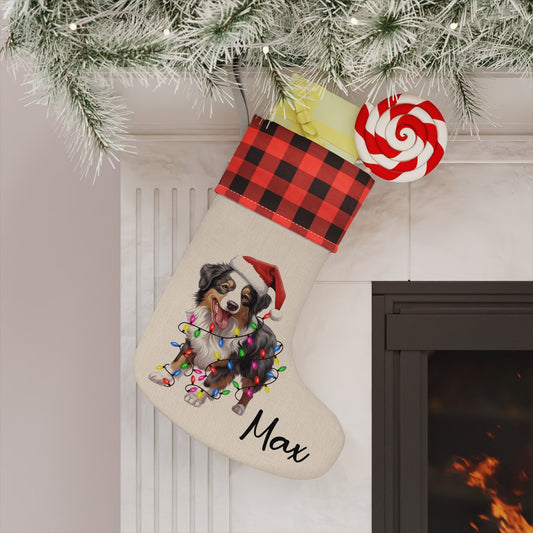 Linen plaid Christmas stocking with a festive Australian Shepherd wrapped in holiday lights, personalized with a dog’s name.