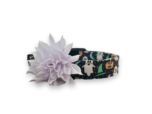 Pastel Halloween dog collar on black background with pumpkins, ghosts, brooms, and skeletons. Includes removable 3” or 4” flower with elastic loop.