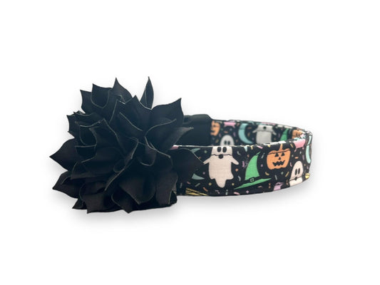 Pastel Halloween dog collar on black background with pumpkins, ghosts, brooms, and skeletons. Includes removable 3” or 4” flower with elastic loop.