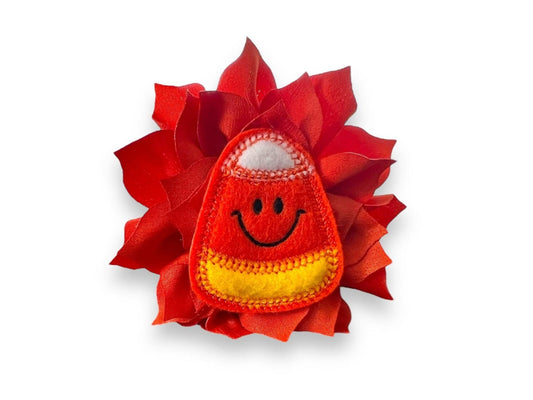 Orange dog collar flower with smiling candy embellishment on a white background.
