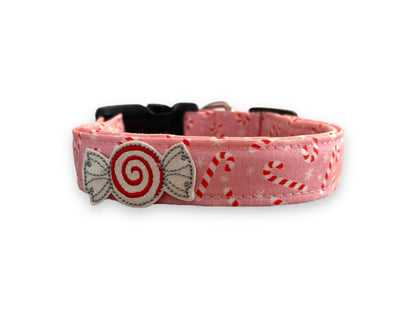 Light pink Christmas dog collar decorated with peppermint candy canes and snowflakes, shown with a shimmery peppermint candy embellishment attached by an elastic loop.