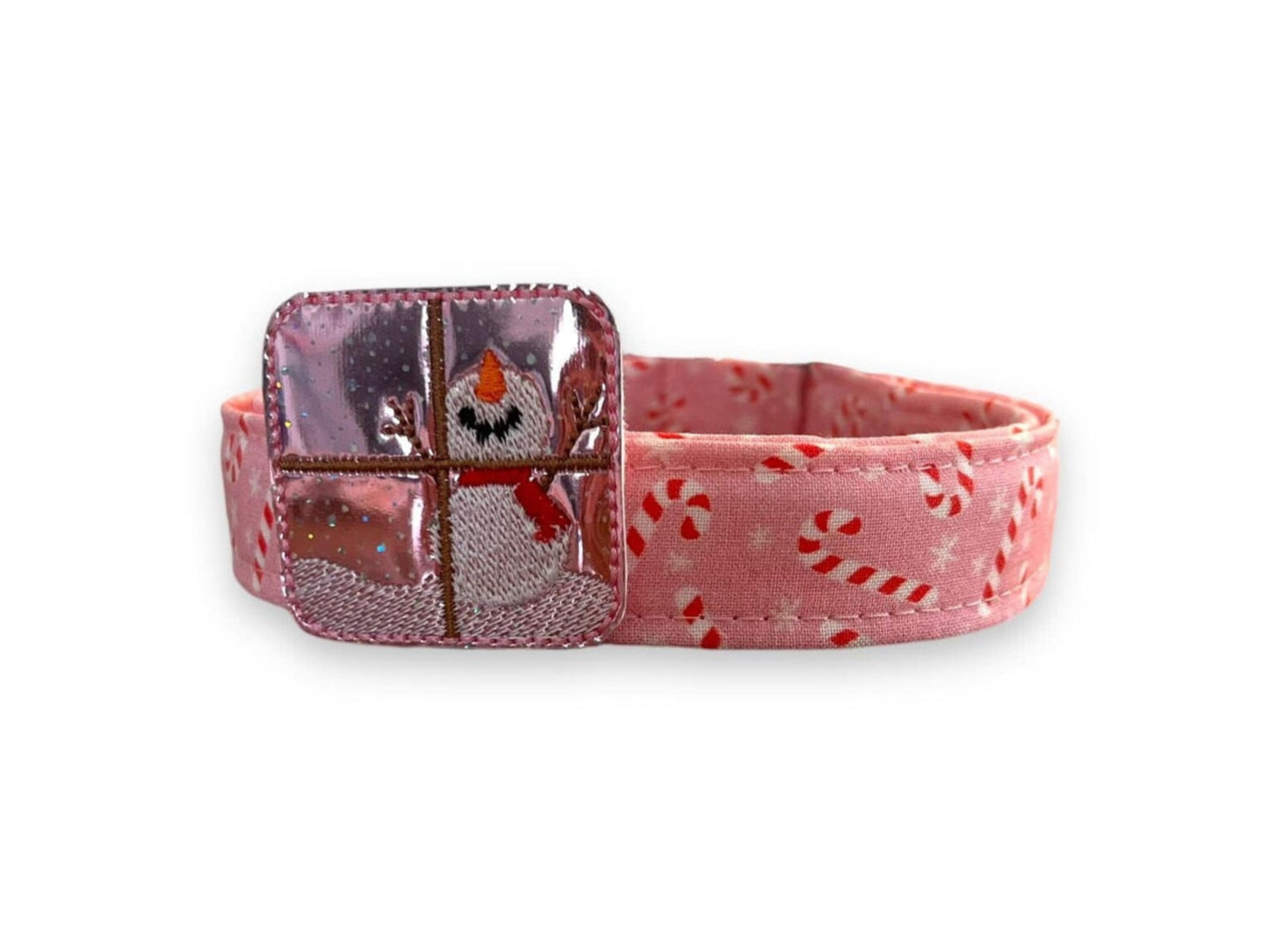 Light pink Christmas dog collar decorated with peppermint candy canes and snowflakes, shown with a shimmery pink snowman-in-window embellishment attached by an elastic loop.