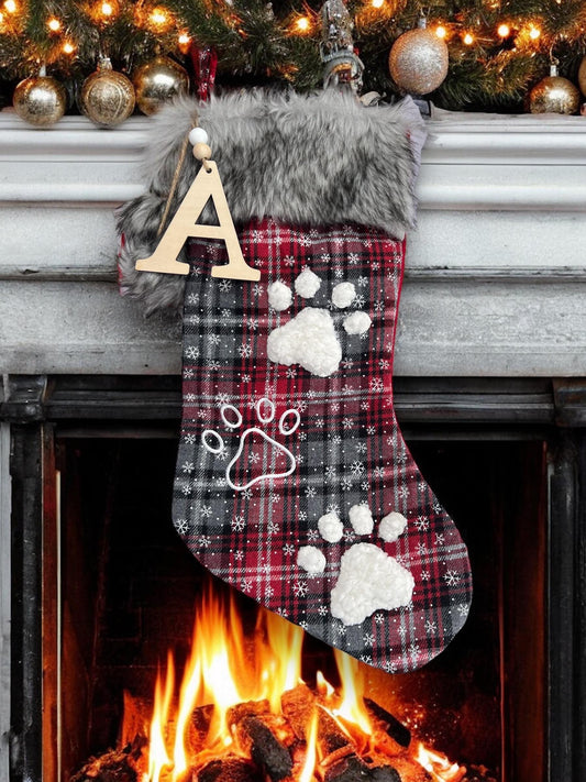 White, red, and gray plaid dog Christmas stocking with embroidered fuzzy paw prints, delicate snowflakes, and a wooden initial charm, perfect for holiday treats.