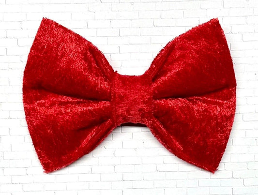 Red velvet dog bow tie with a soft, plush texture, displayed on a white background. The elegant accessory features a deep red hue and  elastic loops on the back for easy attachment.
