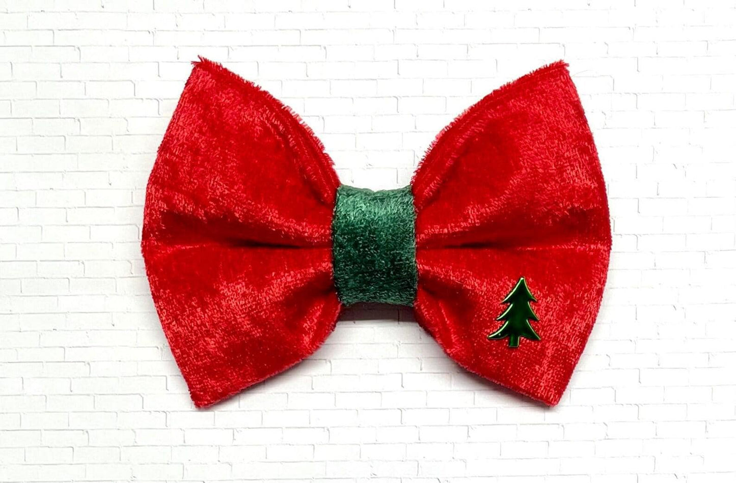 Red and green velvet dog bow tie with a soft, plush texture, displayed on a white background. The festive bow tie features rich holiday colors and a Christmas tree charm. 