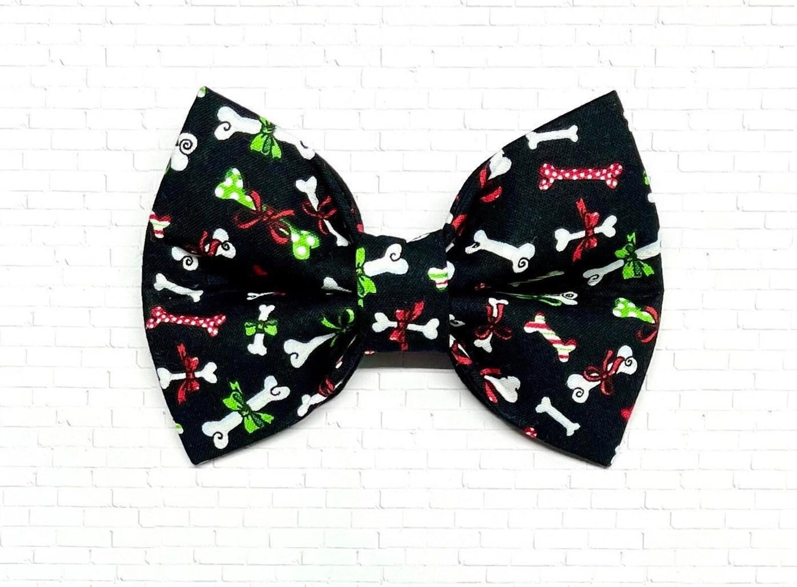 Black Christmas dog bow tie with colorful holiday dog bone pattern, displayed on a white background. The festive bow tie features red, green, and white bones wrapped as Christmas presents.