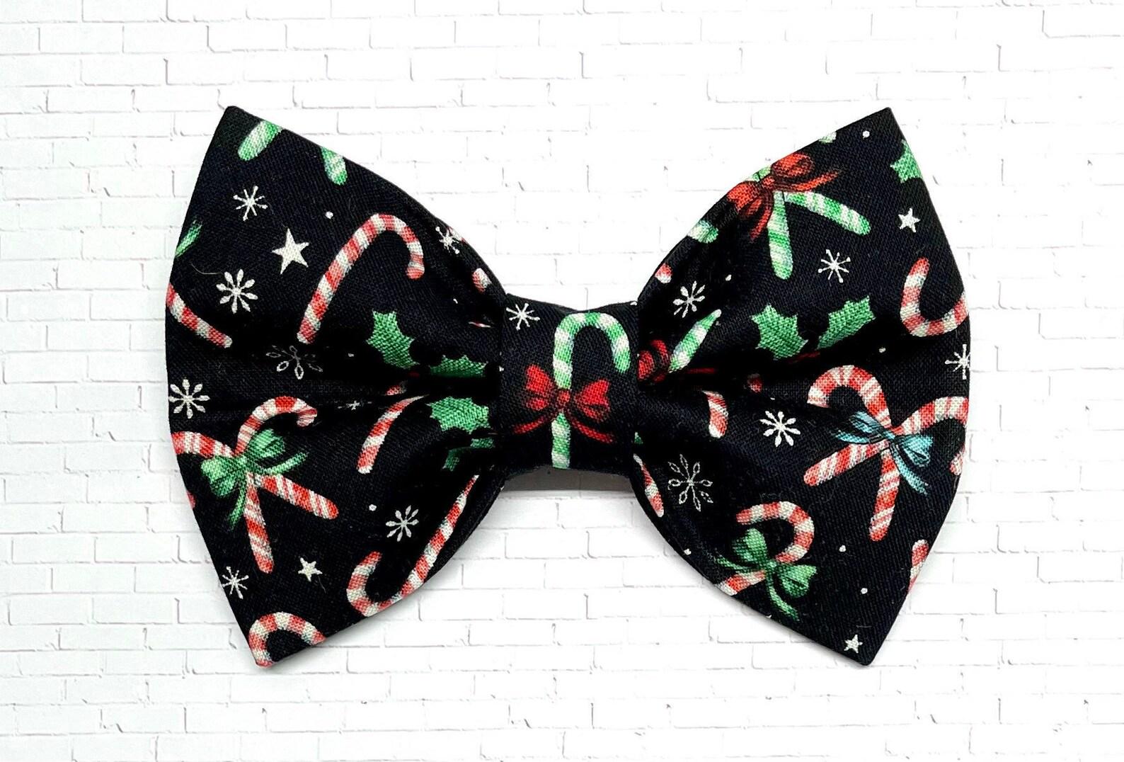 Black Christmas dog bow tie decorated with red, green, and white candy cane designs, displayed on a white background. The handmade bow tie features a festive holiday pattern.