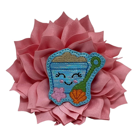 Light Pink dog collar flower with a playful sand bucket embellishment, attached to a pet collar and styled for a fun, beach-themed summer look.
