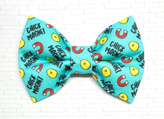 Turquoise dog bow tie with a playful “Chick Magnet” pattern featuring yellow chick faces and red magnets, perfect for flirty, fun-loving pups.