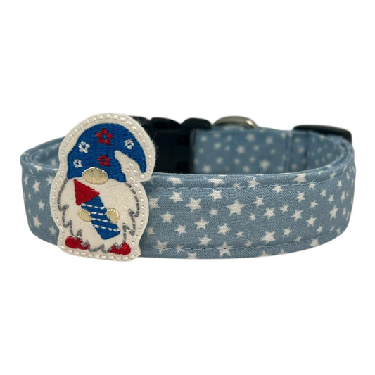 Light blue chambray dog collar with scattered white stars, paired with a removable patriotic firecracker gnome embellishment in red, white, and blue.