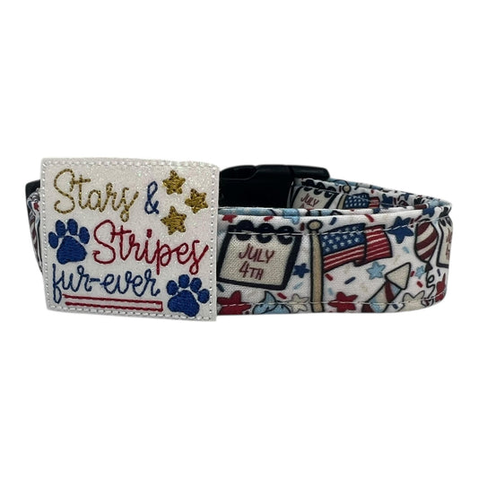 Light-colored 4th of July dog collar decorated with American flags, fireworks, balloons, stars, and "July 4th" signs, featuring a bold red, white, and blue "Stars & Stripes Fur-Ever" embellishment.