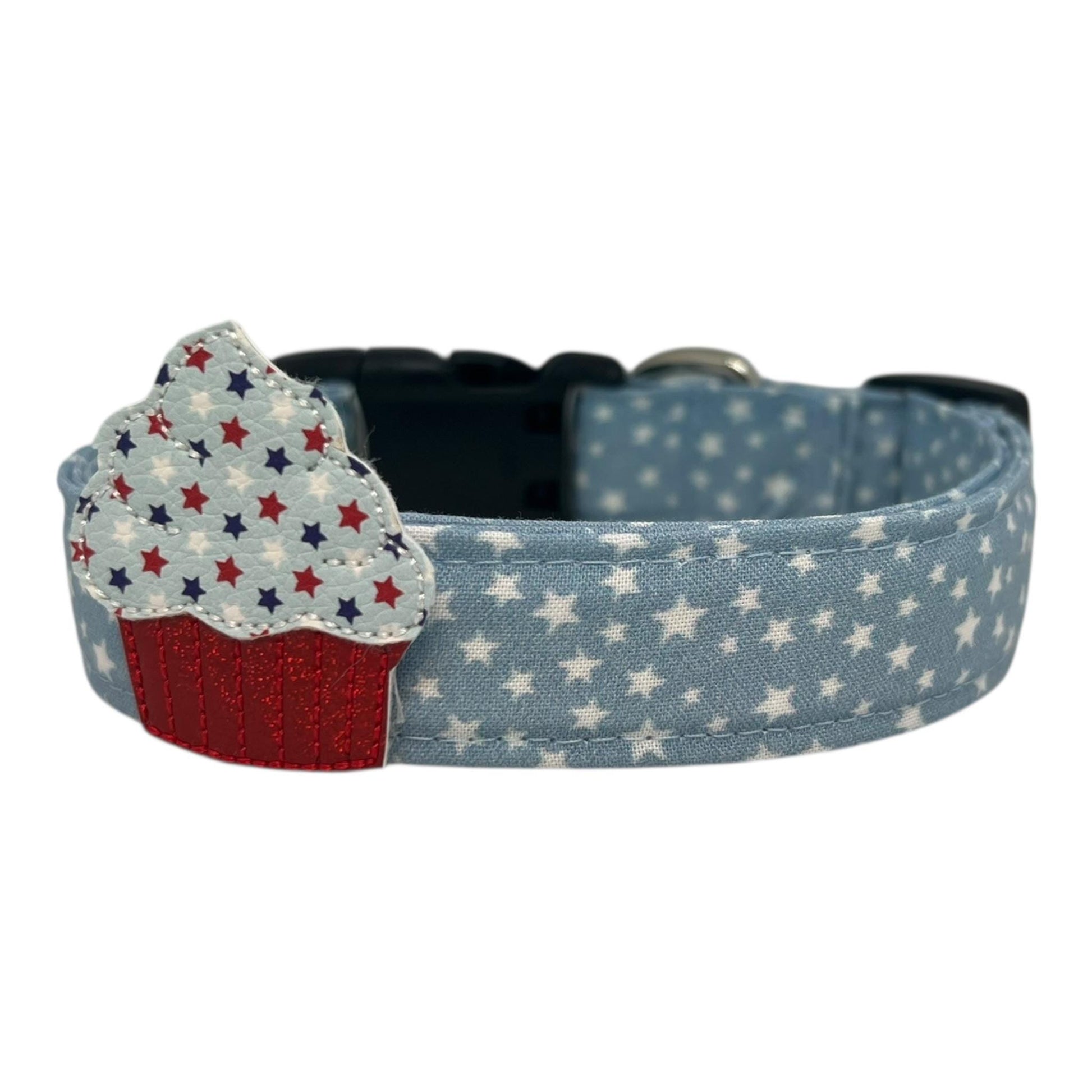 Light blue chambray dog collar with scattered white stars, paired with a removable patriotic cupcake embellishment in red, white, and blue.