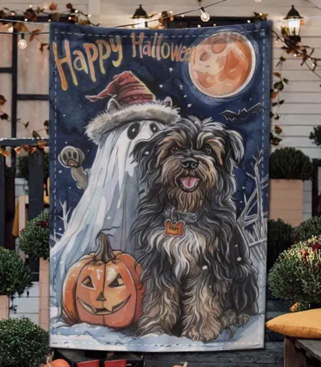 Decorative Halloween flag with a ghost and dog in front of pumpkins and a moon.