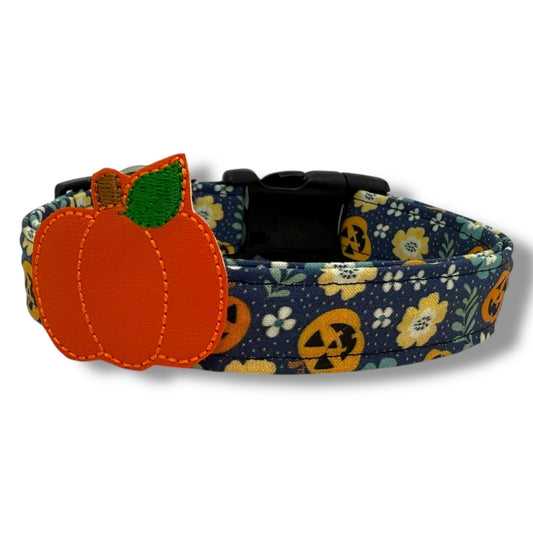 Halloween dog collar with jack-o’-lanterns, floral details, and a removable pumpkin embellishment on a navy blue background.