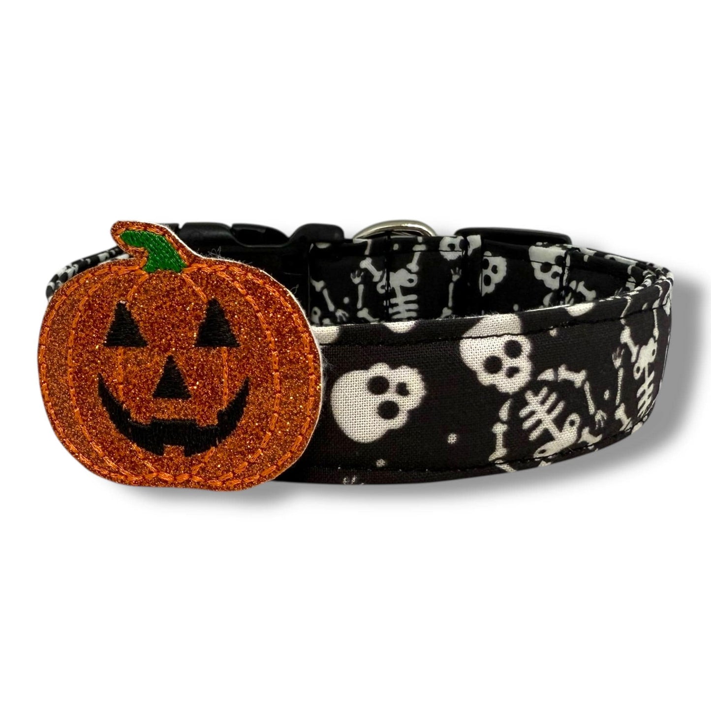 Halloween dog collar with skeletons and skulls on a black background, includes removable shimmery pumpkin embellishment.
