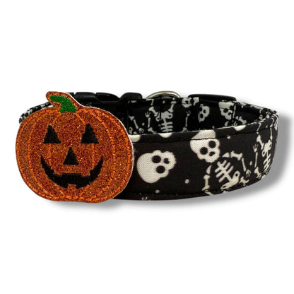 Halloween dog collar with skeletons and skulls on a black background, includes removable shimmery pumpkin embellishment.