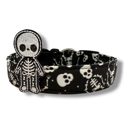 Halloween dog collar with skeletons and skulls on a black background, includes removable shimmery skeleton embellishment.