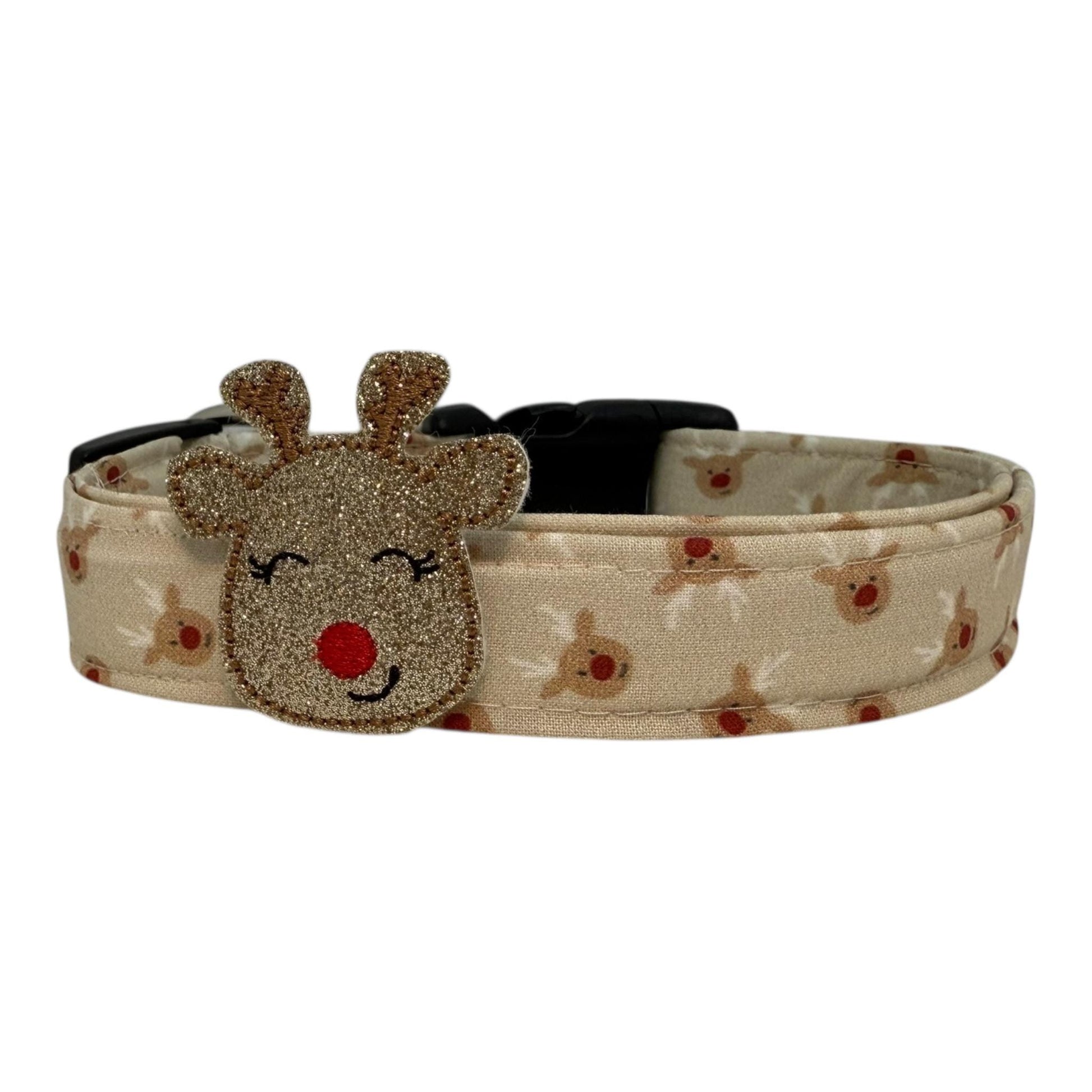 Beige dog collar with small red-nose reindeer faces and a removable shimmery reindeer embellishment, adjustable with black buckle and metal D-ring.
