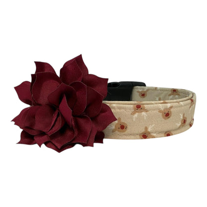 Beige dog collar with small red-nose reindeer faces and a removable flower attachment, adjustable with black buckle and metal D-ring.